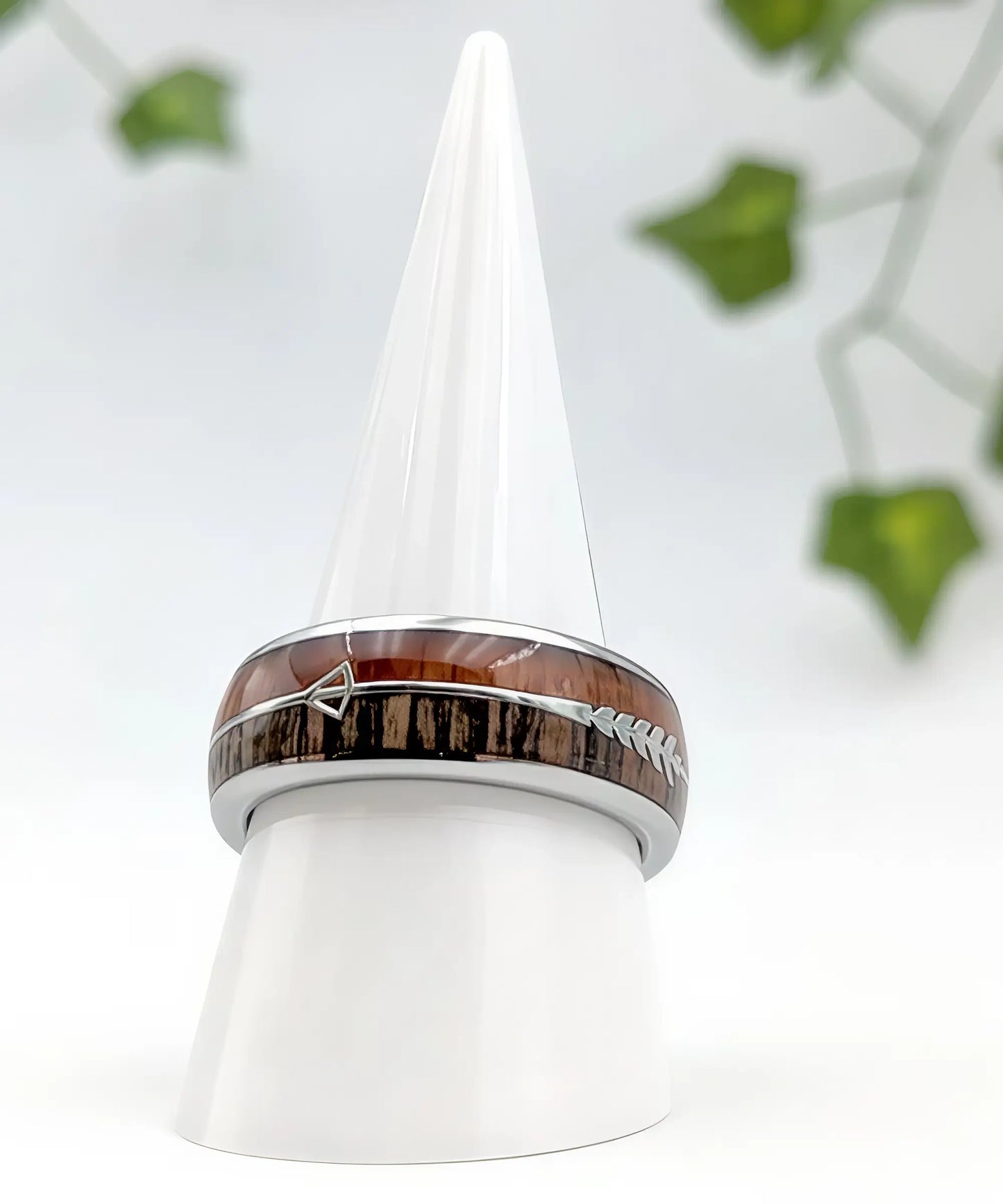 Bague en bois Flèche de Cupidon argent Passion posée sur un présentoir conique blanc, anneau en tungstène poli avec incrustation de bois naturel et flèche argentée symbole d’amour