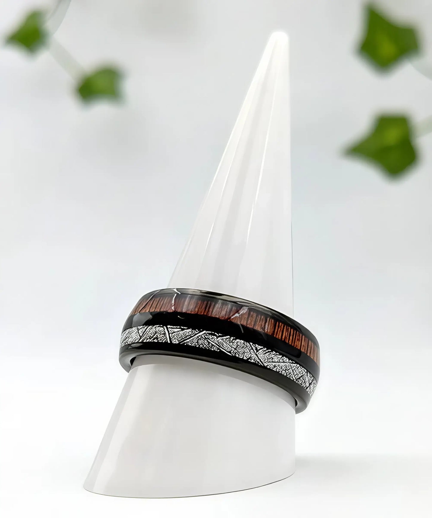 Bague en bois homme Duo d’Eden présentée sur un cône blanc, alliance noire brillante avec incrustation bois exotique et motif argenté