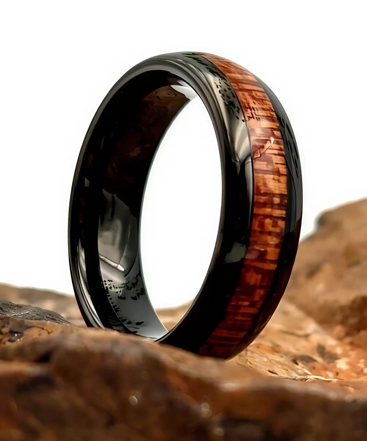 Bague en bois Elior Klimt noire avec incrustation bois brun, posée sur une roche naturelle en gros plan