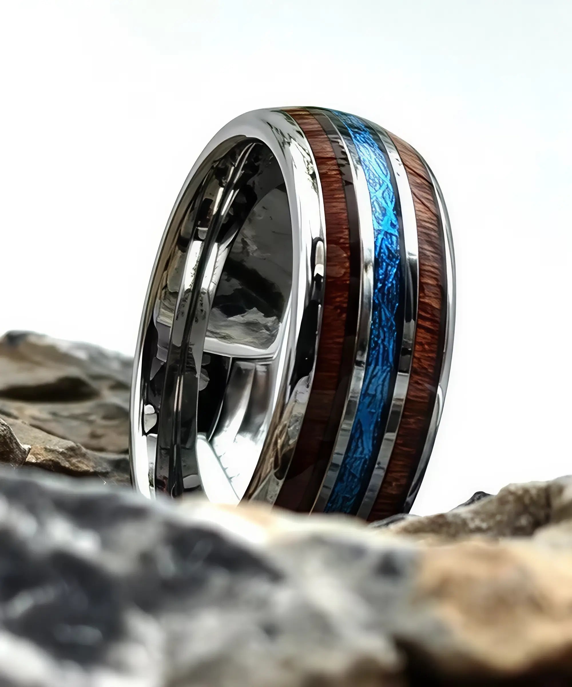 Bague en bois Ark Upto en tungstène avec incrustation bleue et bois koa, posée sur des roches naturelles