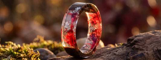 bague bois et résine rouge transparente avec inclusions brillantes bijou artisanal effet lumière sur fond nature
