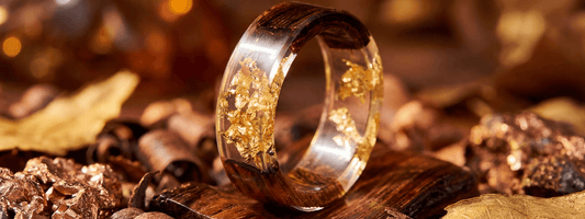 bague bois et résine transparente avec feuilles d’or bijou artisanal luxe naturel posé sur écorce chaude