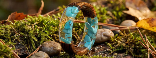 bague bois et résine turquoise avec inclusions dorées bijou artisanal effet pierre naturelle sur fond forêt