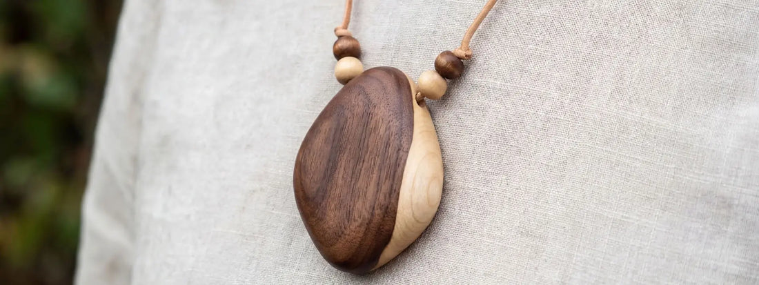 collier en bois naturel pendentif bicolore porté sur tissu lin bijou artisanal style naturel élégant