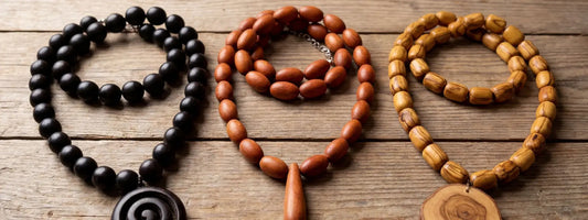 colliers en bois différentes essences ébène santal olivier perles naturelles bijoux artisanaux sur table bois