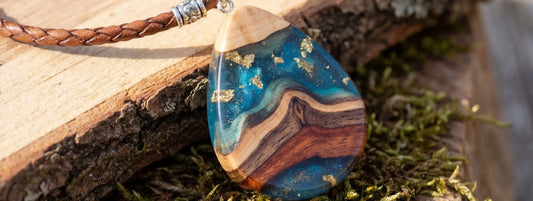 pendentif bois et résine bleu effet rivière avec inclusions dorées bijou artisanal nature sur fond bois