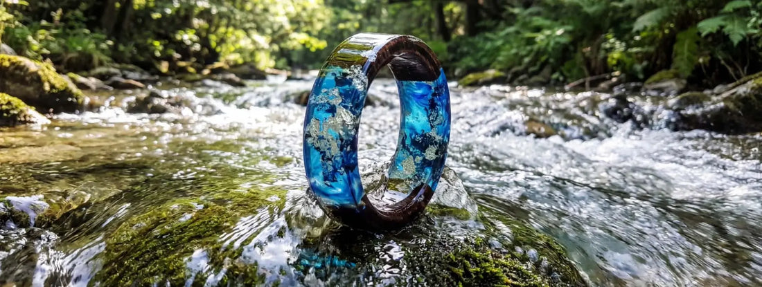 bague bois et résine bleue effet rivière naturelle bijou artisanal en milieu forestier sur roche avec eau claire