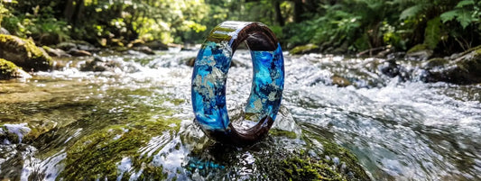 bague bois et résine bleue effet rivière naturelle bijou artisanal en milieu forestier sur roche avec eau claire