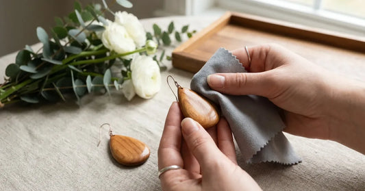 Mains entretenant délicatement des boucles d'oreilles en bois avec un chiffon doux