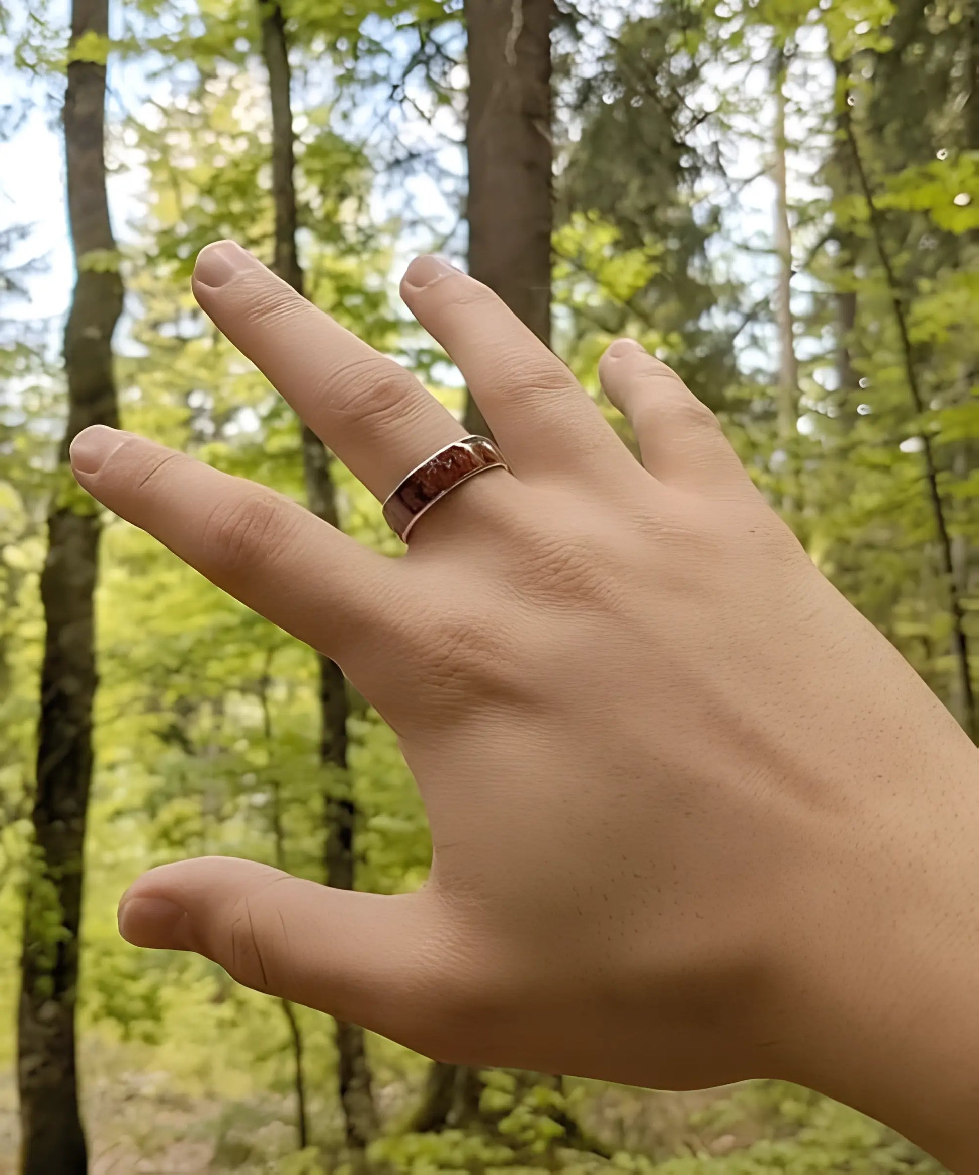 Bague homme Ouranos en bois de koa et tungstène argent portée à la main en pleine forêt - alliance élégante et naturelle