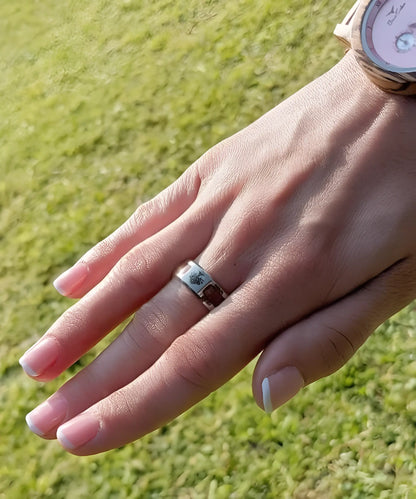 Main féminine portant une bague en bois et acier inoxydable gravée Arbre de Vie, alliance naturelle et élégante.