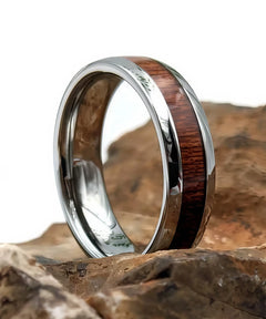 Bague en bois et argent Elior Klimt, alliance en tungstène argenté avec incrustation de bois sombre, posée sur des rochers pour une mise en valeur naturelle et élégante.