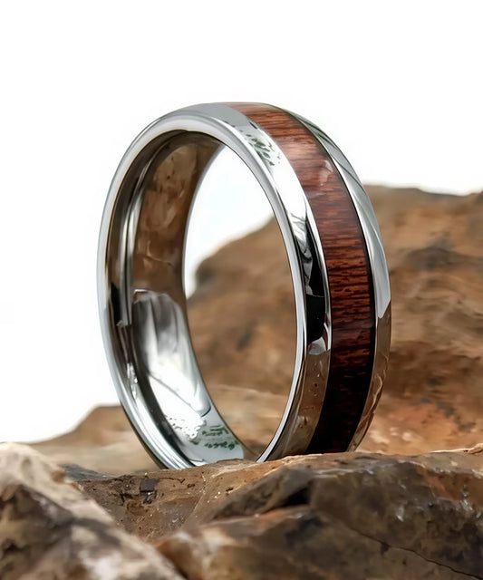 Bague en bois et argent Elior Klimt, alliance en tungstène argenté avec incrustation de bois sombre, posée sur des rochers pour une mise en valeur naturelle et élégante.