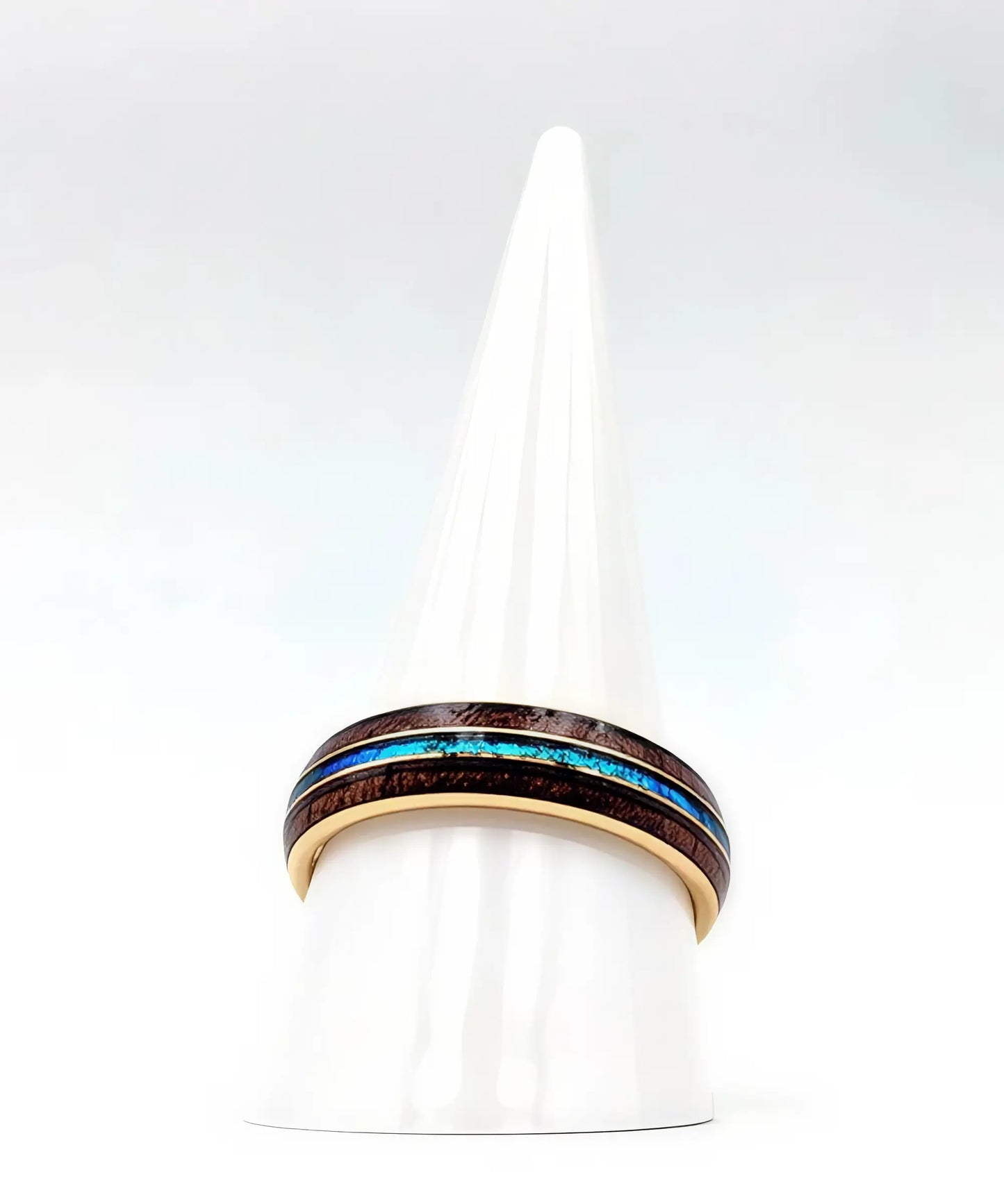 Bague en bois Ark en or jaune avec incrustation turquoise posée sur un présentoir conique blanc