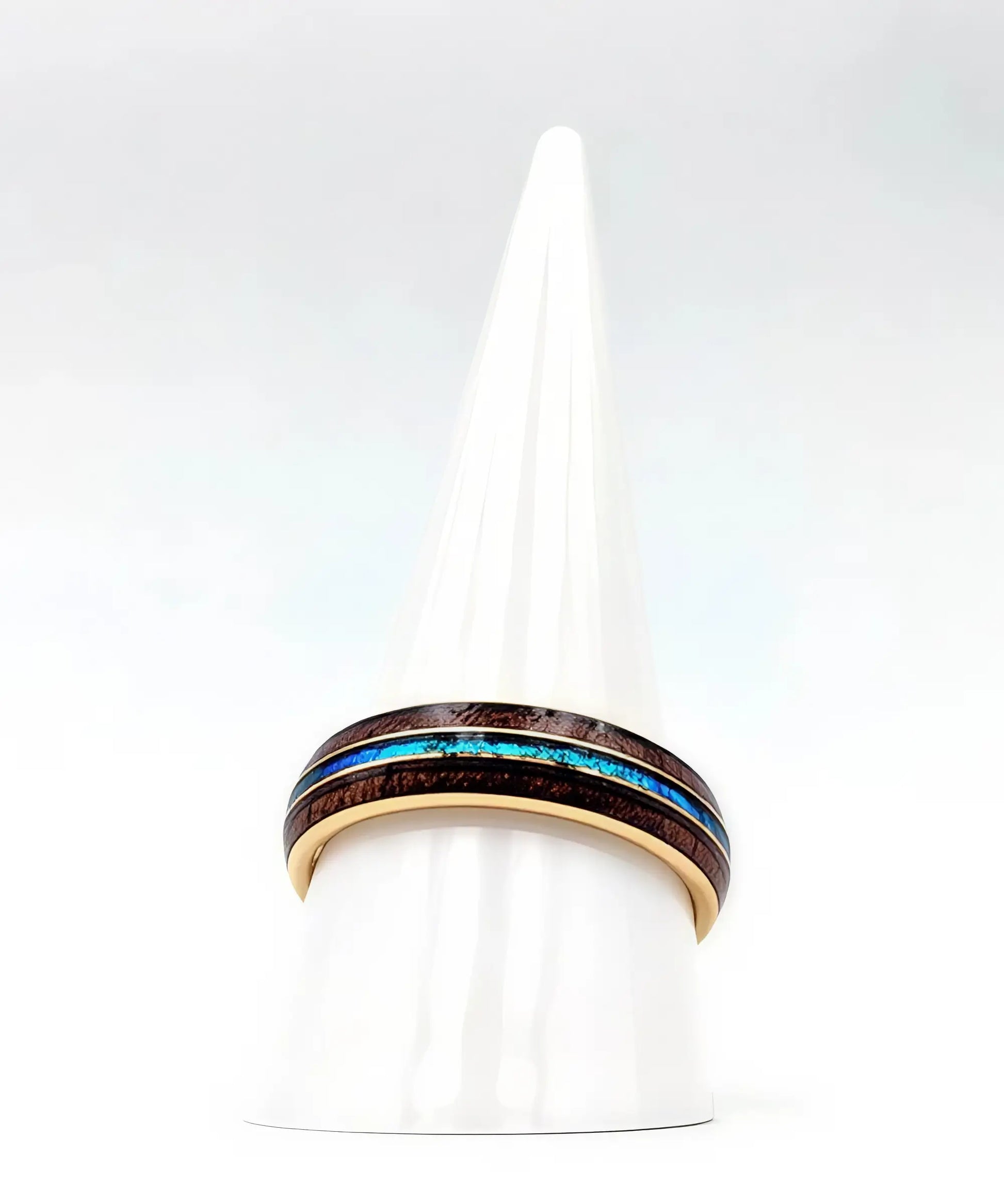 Bague en bois Ark en or jaune avec incrustation turquoise posée sur un présentoir conique blanc