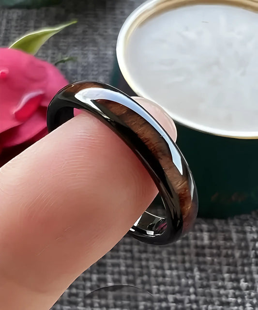Bague en bois Couple Elior Tana noire portée au doigt, incrustation de bois sombre et finition en tungstène noir élégant