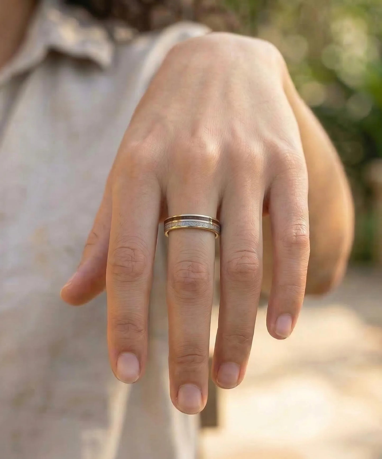 Bague en bois Duo d’Eden Sim or portée sur la main d’une femme, alliance en bois naturel et métal doré au style élégant et minimaliste.