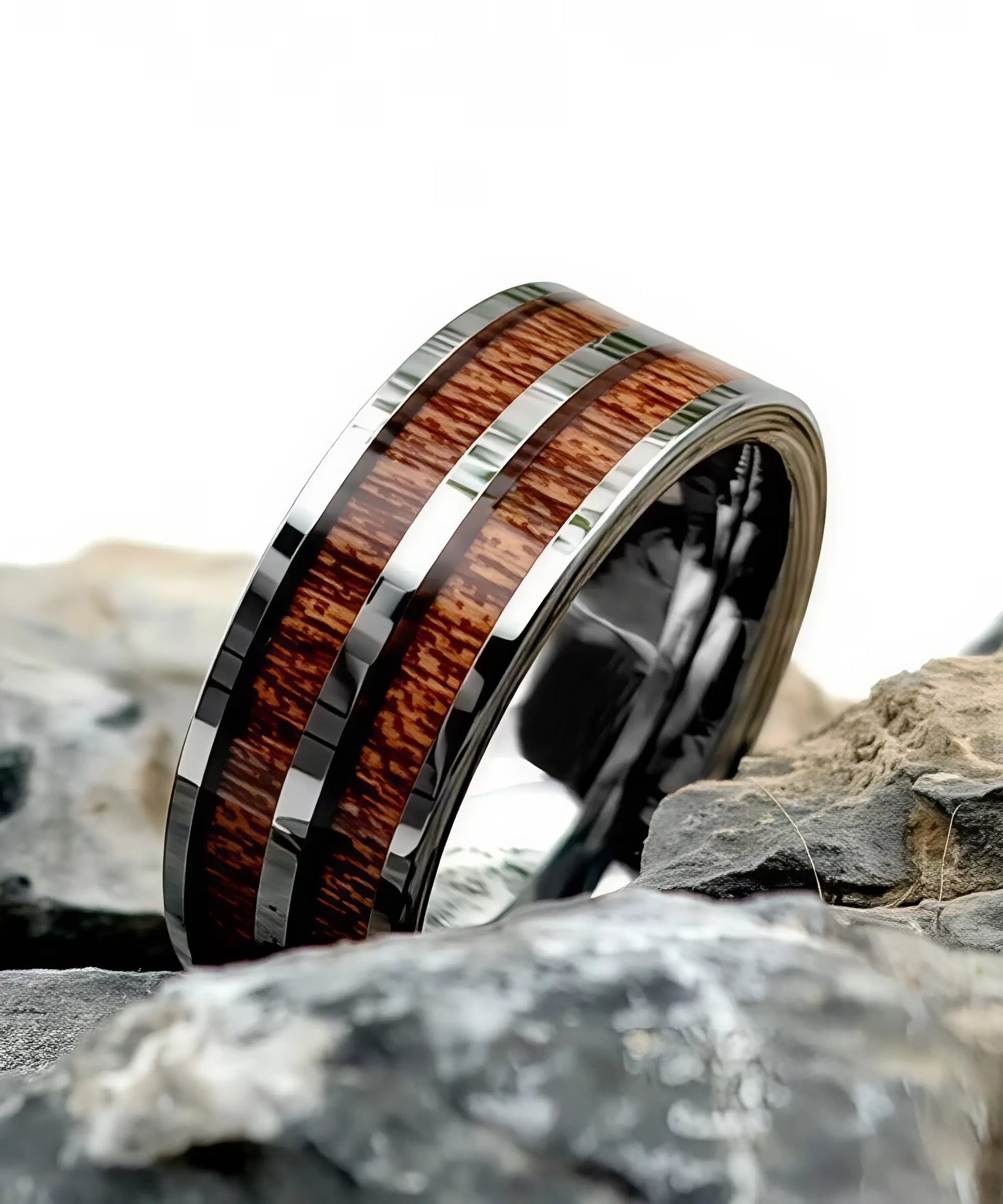 Bague Duo Primordial Adam en tungstène et bois de koa avec deux incrustations, posée sur des roches, bijou masculin élégant et naturel.