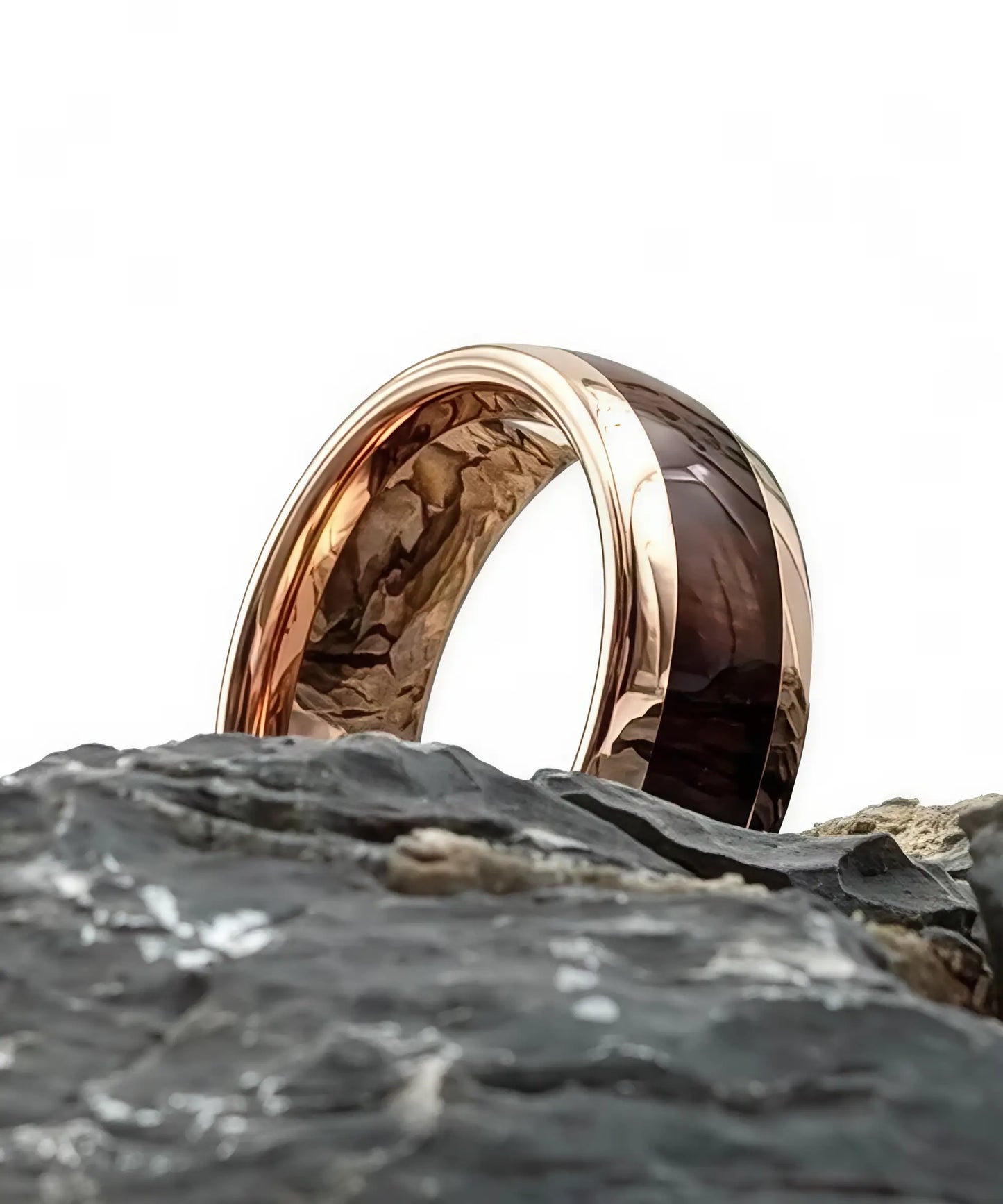 Bague en bois Elior Révo posée sur un rocher, incrustation de bois sombre et finition métal rose doré brillante