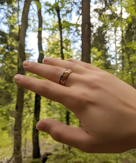 Main portant la bague en bois Flèche de Cupidon argent Passion, anneau en tungstène et bois de koa avec motif flèche, photographié en pleine nature