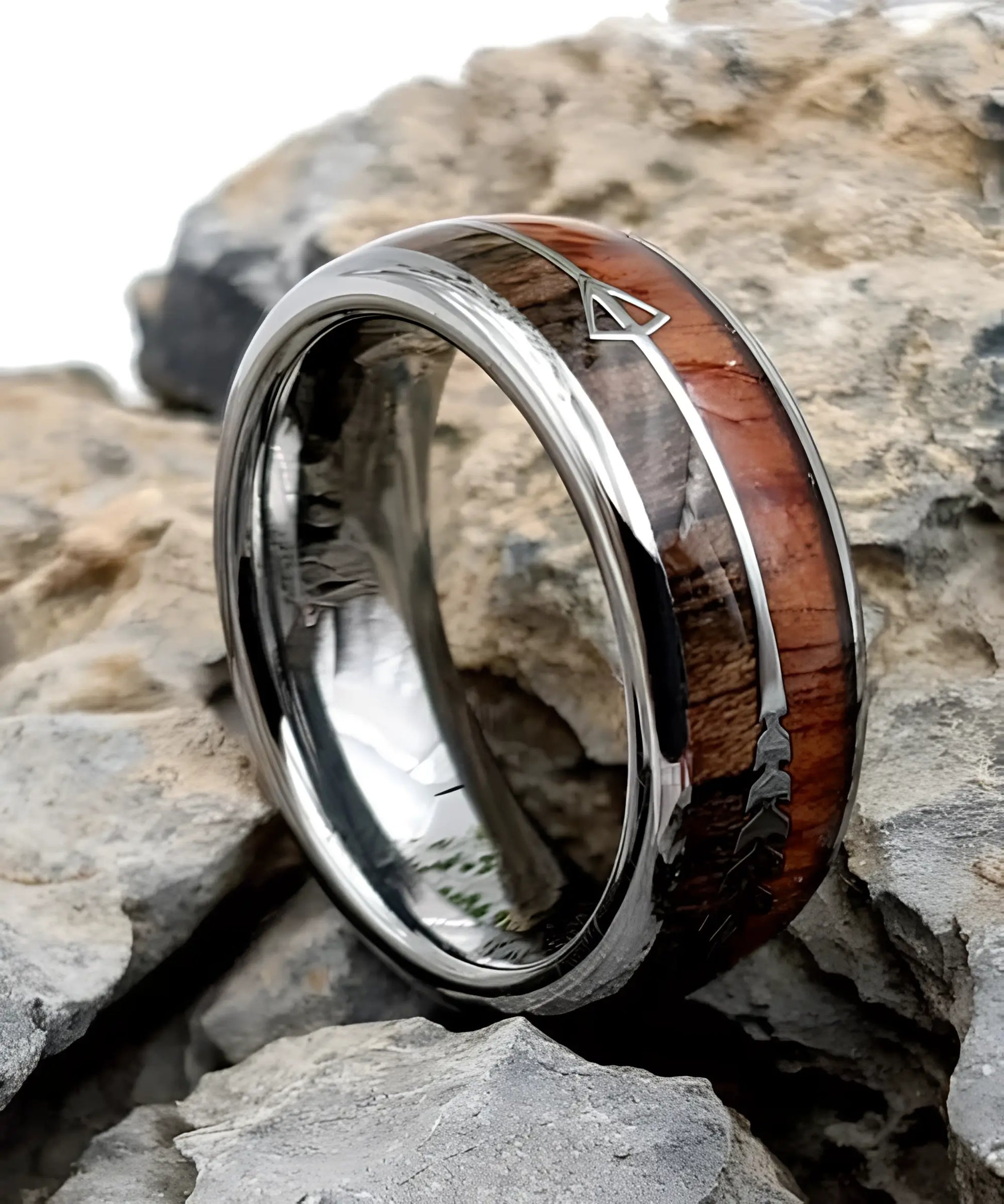 Bague en bois Flèche de Cupidon argent Passion posée sur des roches, anneau en tungstène et bois naturel avec motif flèche symbolisant l’amour et la passion