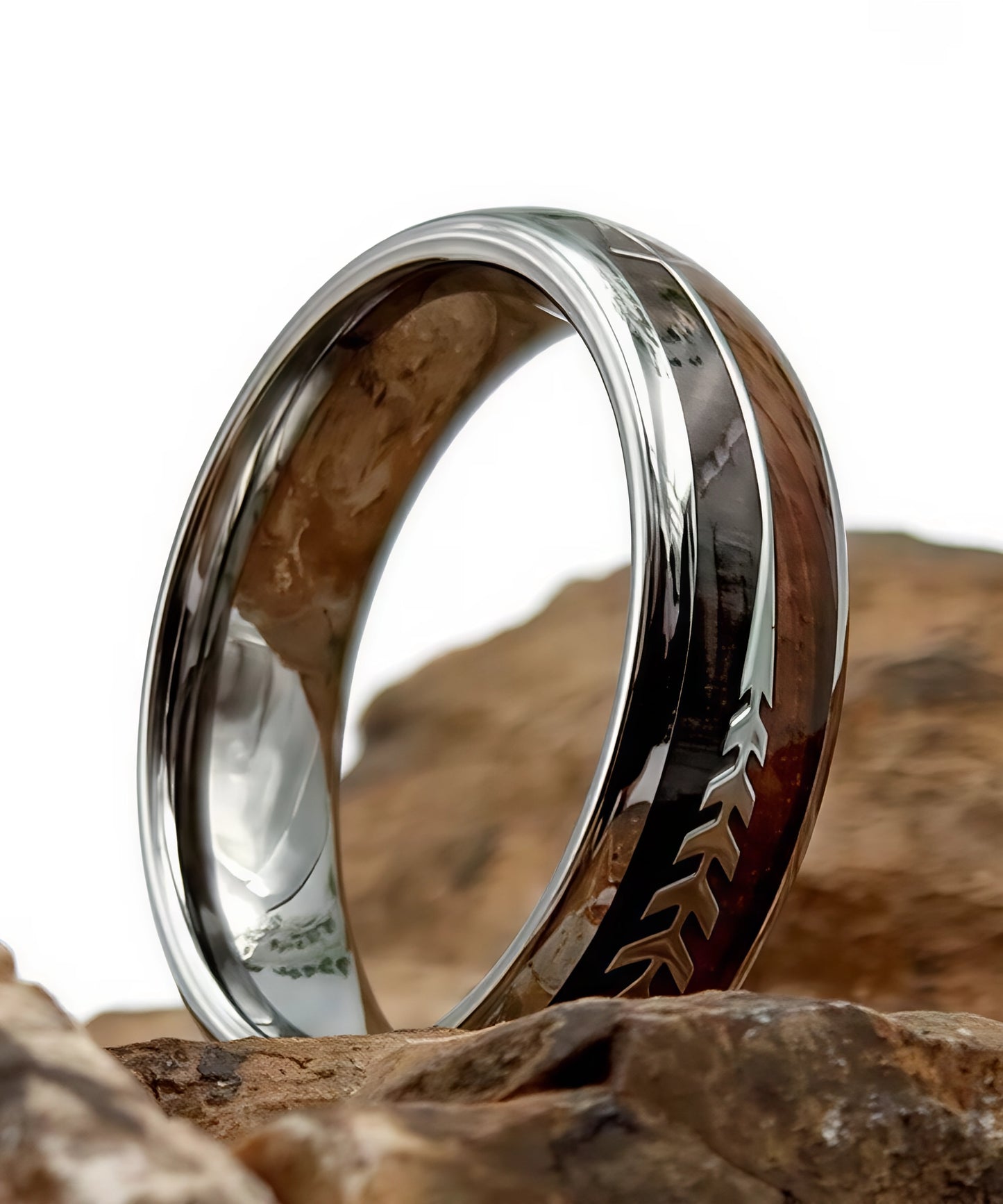 Gros plan sur la bague en bois Flèche de Cupidon Argent Passion Sim, alliance en tungstène argenté avec incrustation de bois et motif flèche gravé, posée sur des rochers.
