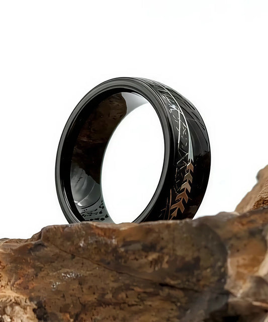Bague Flèche de Cupidon noire Caprice en bois et tungstène noir posée sur une roche, motif flèche argentée, design élégant et moderne.