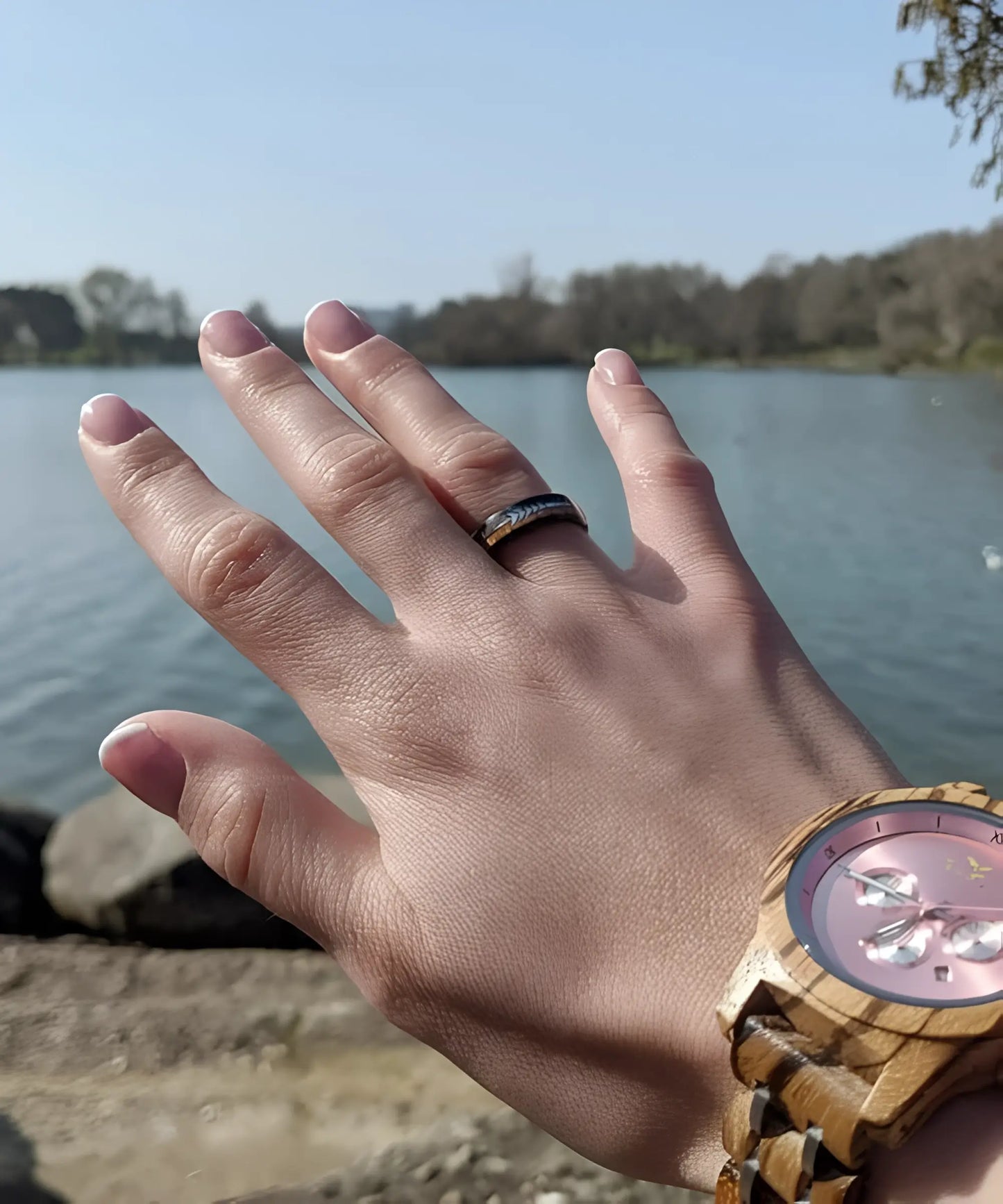 Bague en bois Flèche de Cupidon noire Passion Sim 6 mm en tungstène noir avec incrustation de bois de koa et flèche argentée, portée à la main près d’un lac avec une montre en bois.