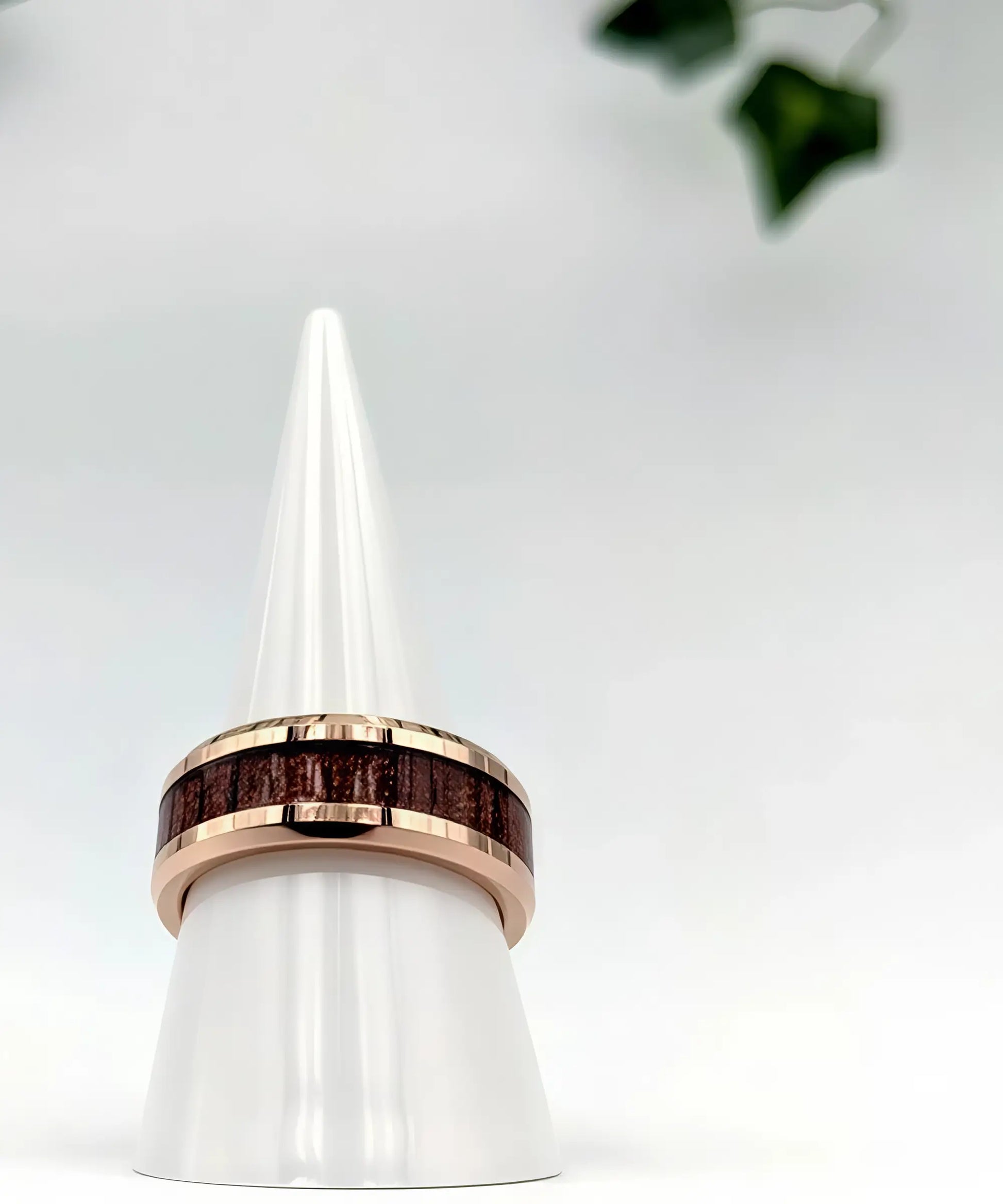 Bague en bois de koa incrustée dans un anneau en tungstène or rose, posée sur un présentoir blanc élégant.
