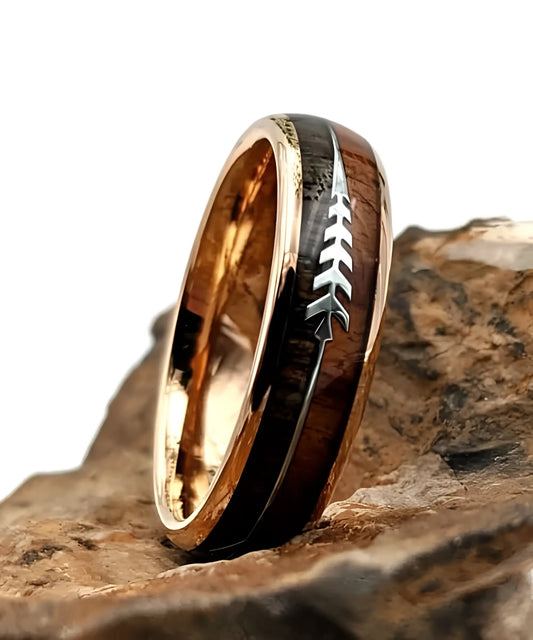 Bague en bois Flèche de Cupidon rose Passion Sim, anneau en tungstène or rose avec incrustation bois naturel et motif flèche, posée sur une roche