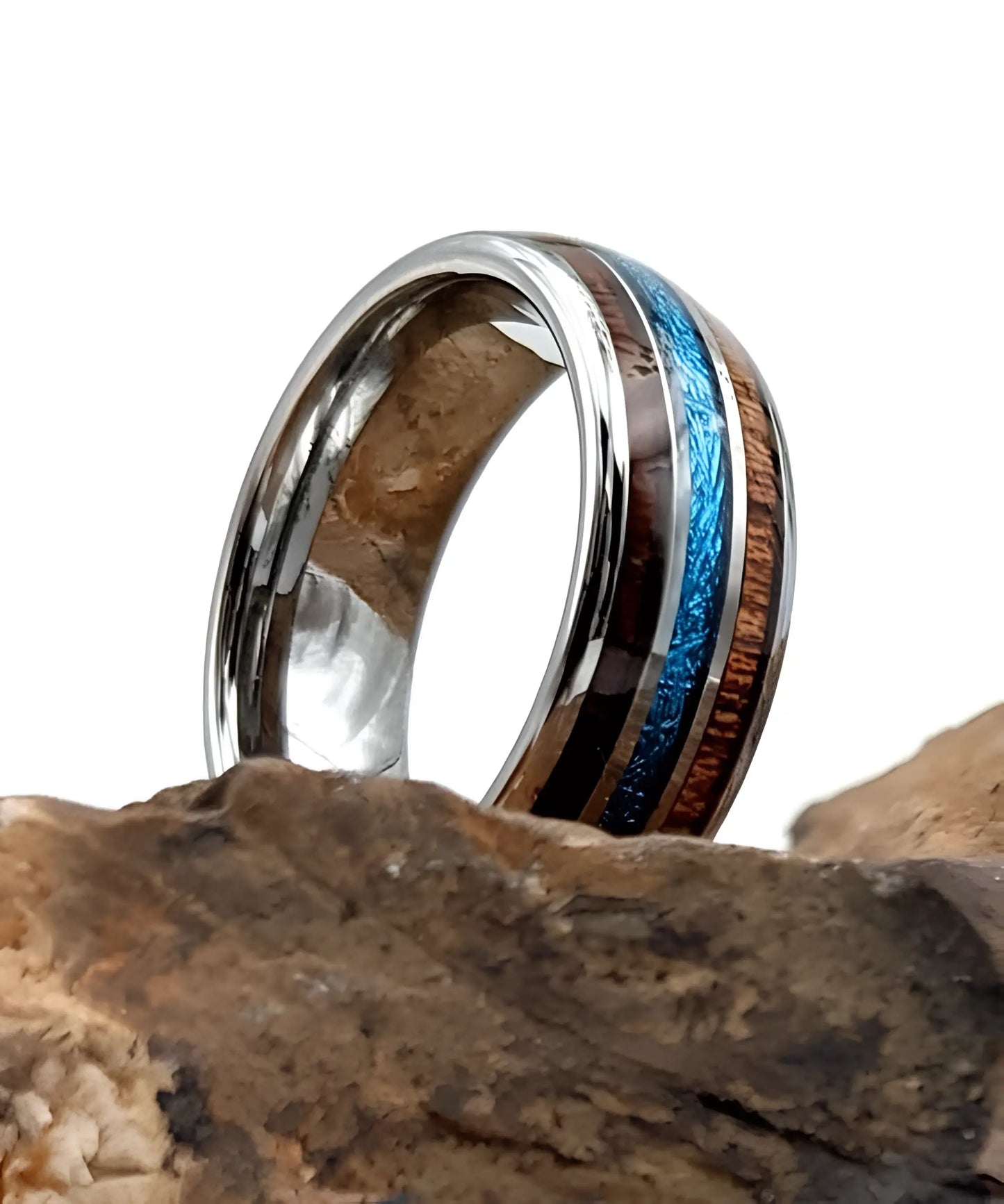 Bague en bois Ark Upto en tungstène posée sur une roche, avec deux bandes de bois koa et une incrustation centrale bleue effet vermiculite