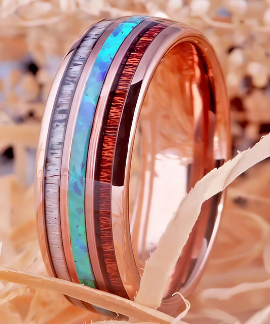 Bague en bois et tungstène rose avec incrustations d’opale bleue, bois de koa et bois de cerf, bijou raffiné présenté en décor naturel