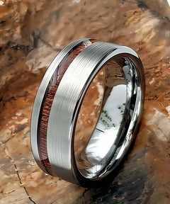 Bague en bois Ultron Ram argent en tungstène finition brossée avec incrustation de bois de koa, posée sur une roche naturelle texturée