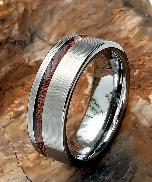 Bague en bois Ultron Ram argent en tungstène finition brossée avec incrustation de bois de koa, posée sur une roche naturelle texturée