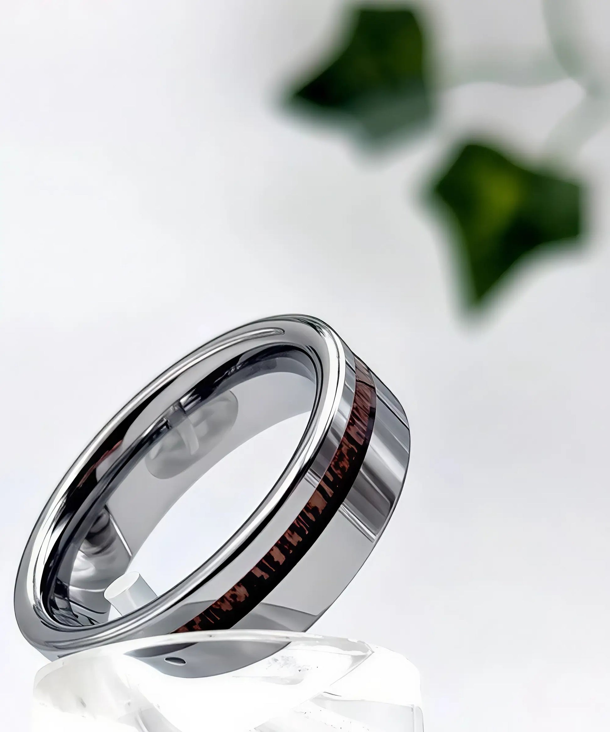 Bague en bois Ultron Sim argent en tungstène poli avec incrustation de bois de koa, posée sur un support en cristal, vue élégante et raffinée