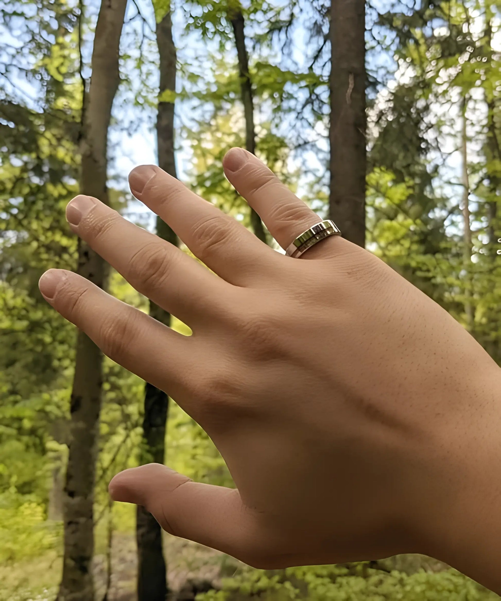 Main portant la bague en bois Ultron Sim argent en tungstène poli avec incrustation de bois de koa, en pleine nature