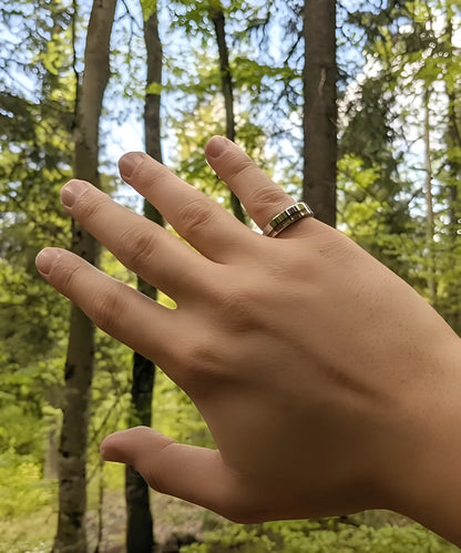 Main portant la bague en bois Ultron Sim argent en tungstène poli avec incrustation de bois de koa, en pleine nature
