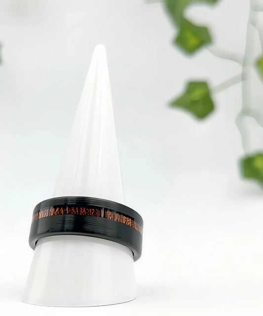 Bague homme en tungstène noir brossé avec incrustation de bois rouge Ultron, posée sur un présentoir blanc