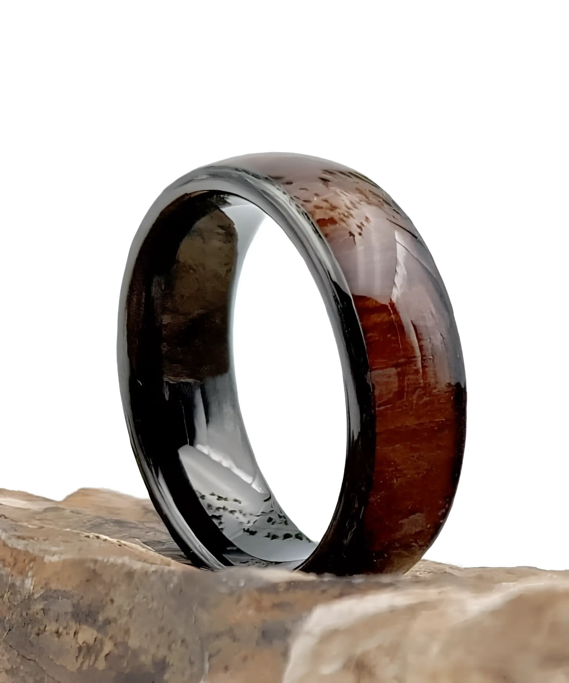 Bague Ouranos noire en tungstène et bois de koa posée sur une pierre, alliance entre robustesse et naturel