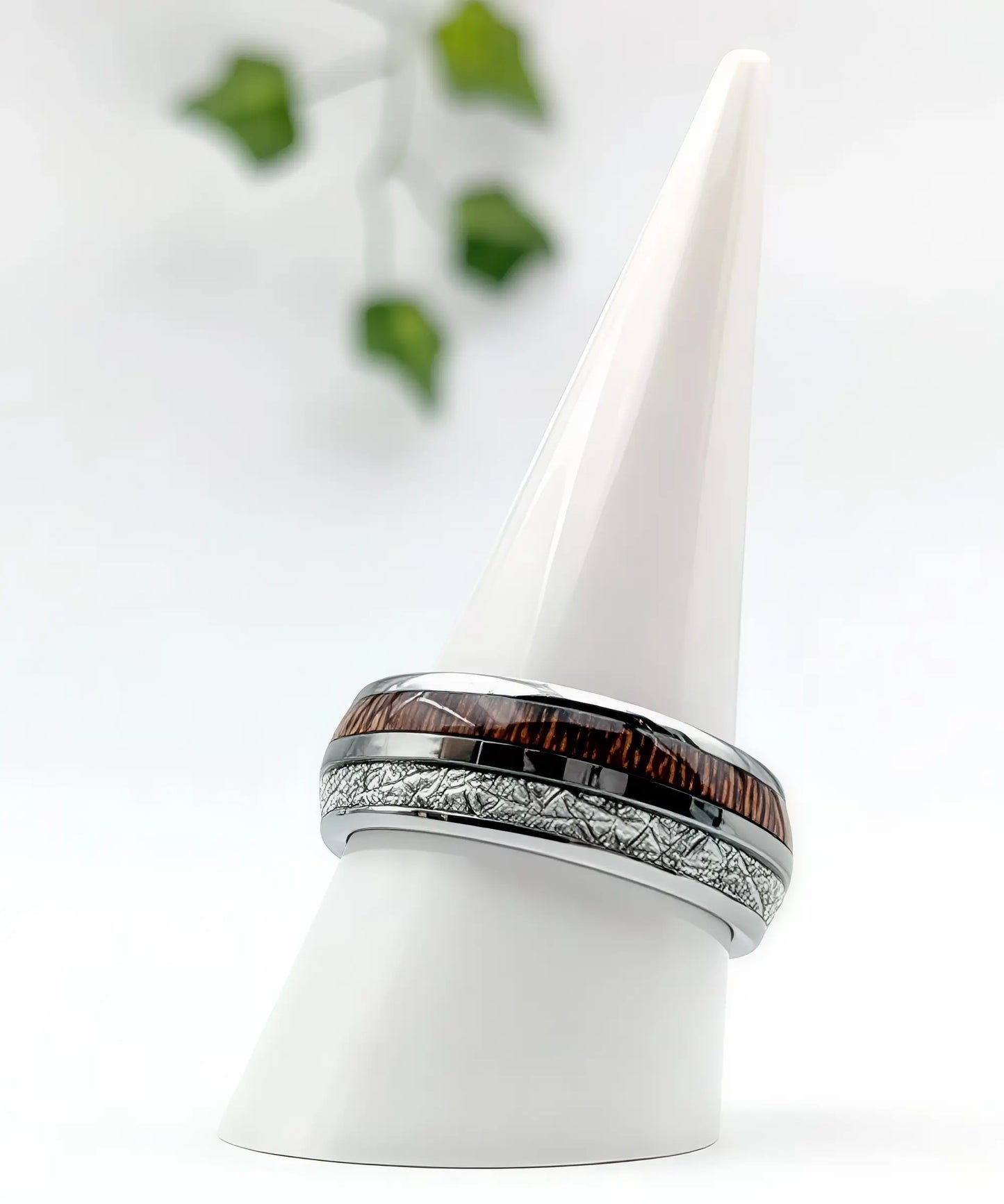 Bague en tungstène avec incrustation de bois de koa et bande aspect météorite présentée sur un cône blanc, design moderne et raffiné.