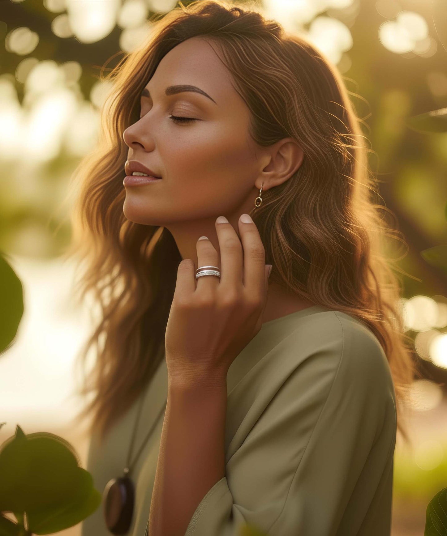 Femme en extérieur au coucher du soleil, yeux fermés, mettant en avant une bague en bois et tungstène sur sa main.