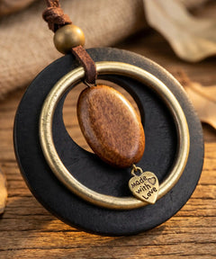 Pendentif bois sur planche en bois rustique entoure de feuilles d'automne, ambiance nature

