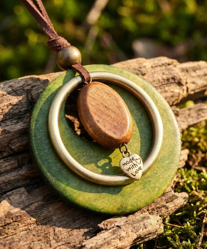 Pendentif bois vert avec breloque coeur sur tronc moussu en exterieur, bijou boheme nature
